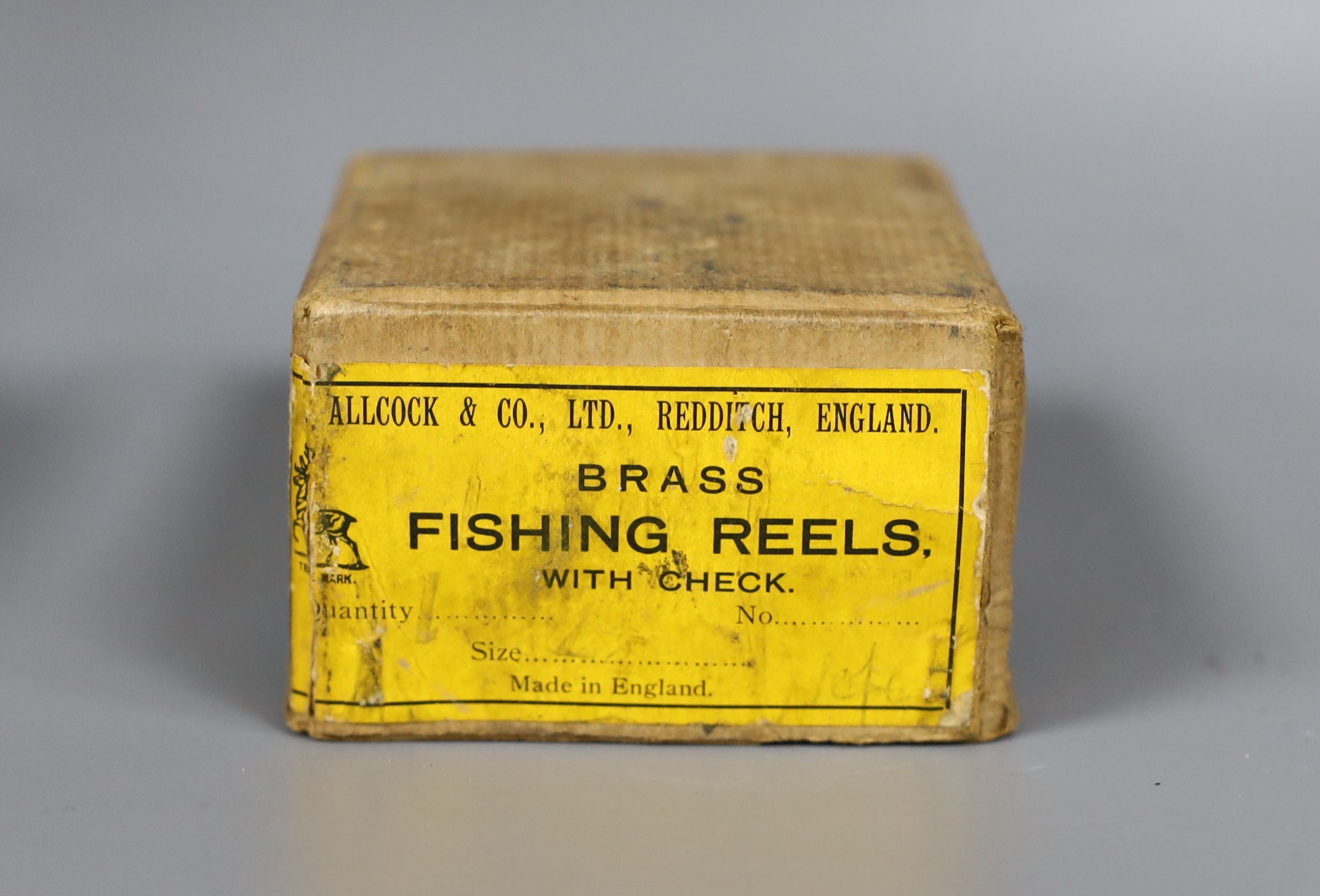 An Allcock brass fishing reel, 6cm. diam., in original box